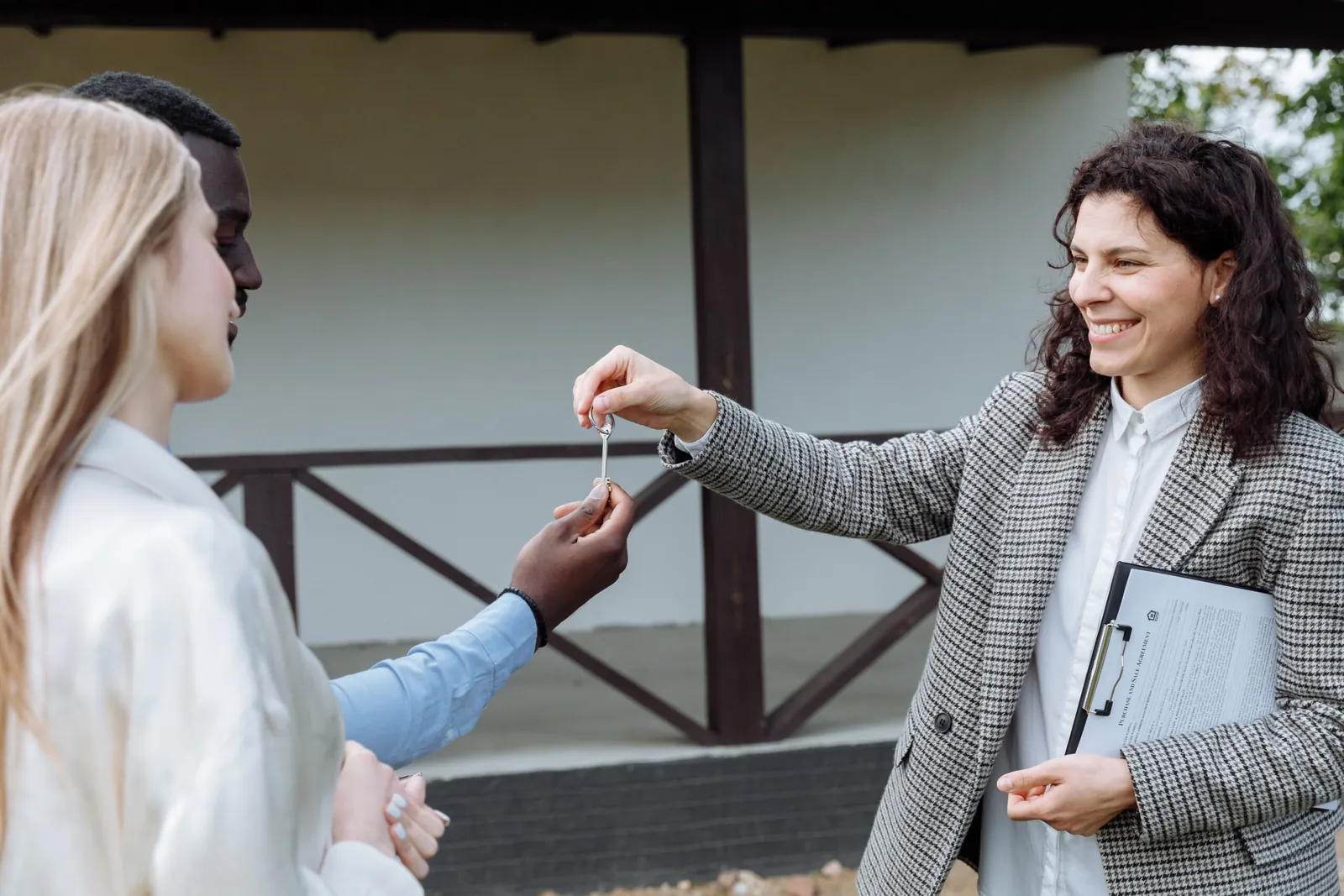 Agent handing house keys to a smiling client on a porch