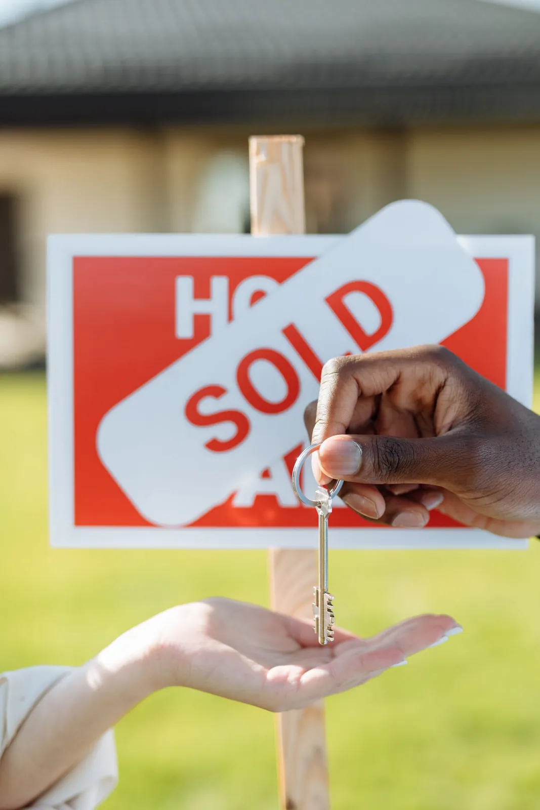 Sold sign held in front of a For Sale yard sign