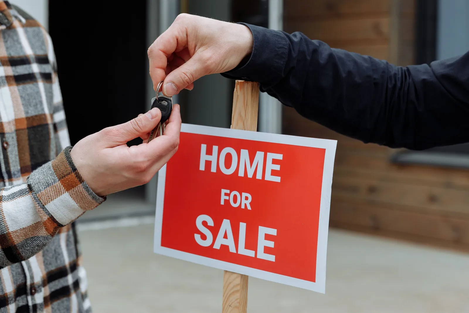 House keys handed over beside a red Home for Sale sign