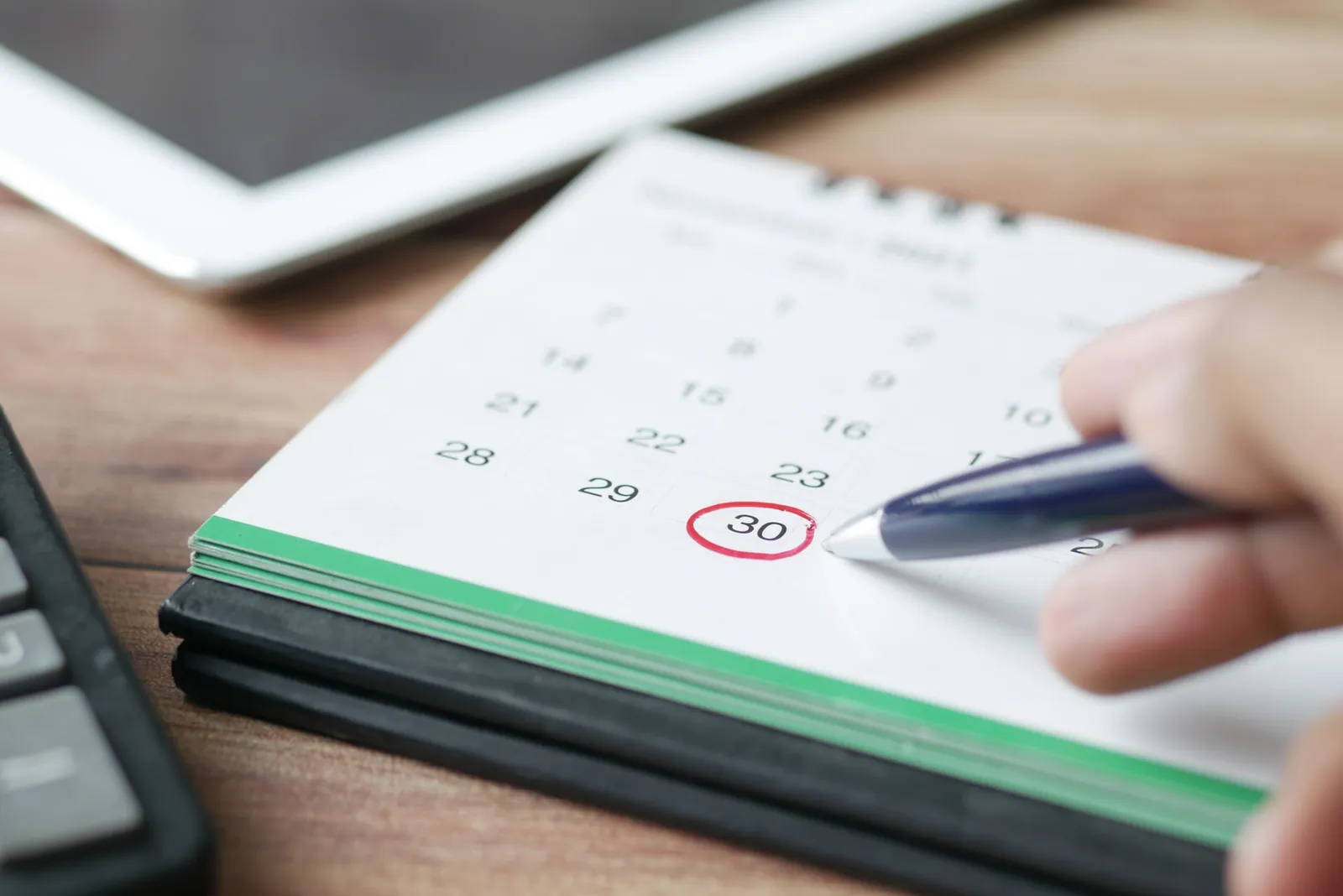 Hand circling a closing date on a desk calendar