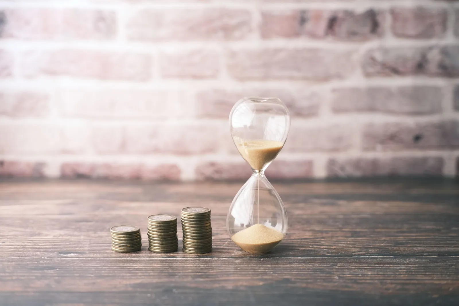 Stacks of coins growing beside an hourglass