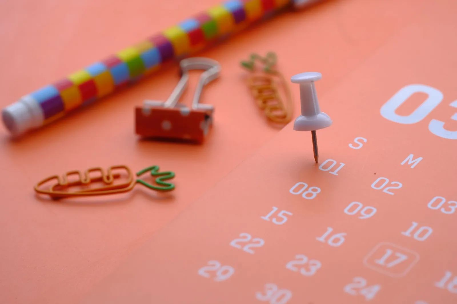 Calendar page with push pins and colorful clips