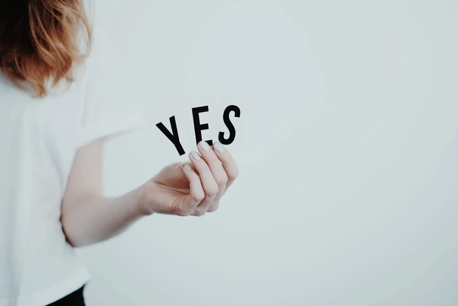 Hand holding paper letters spelling 'YES'
