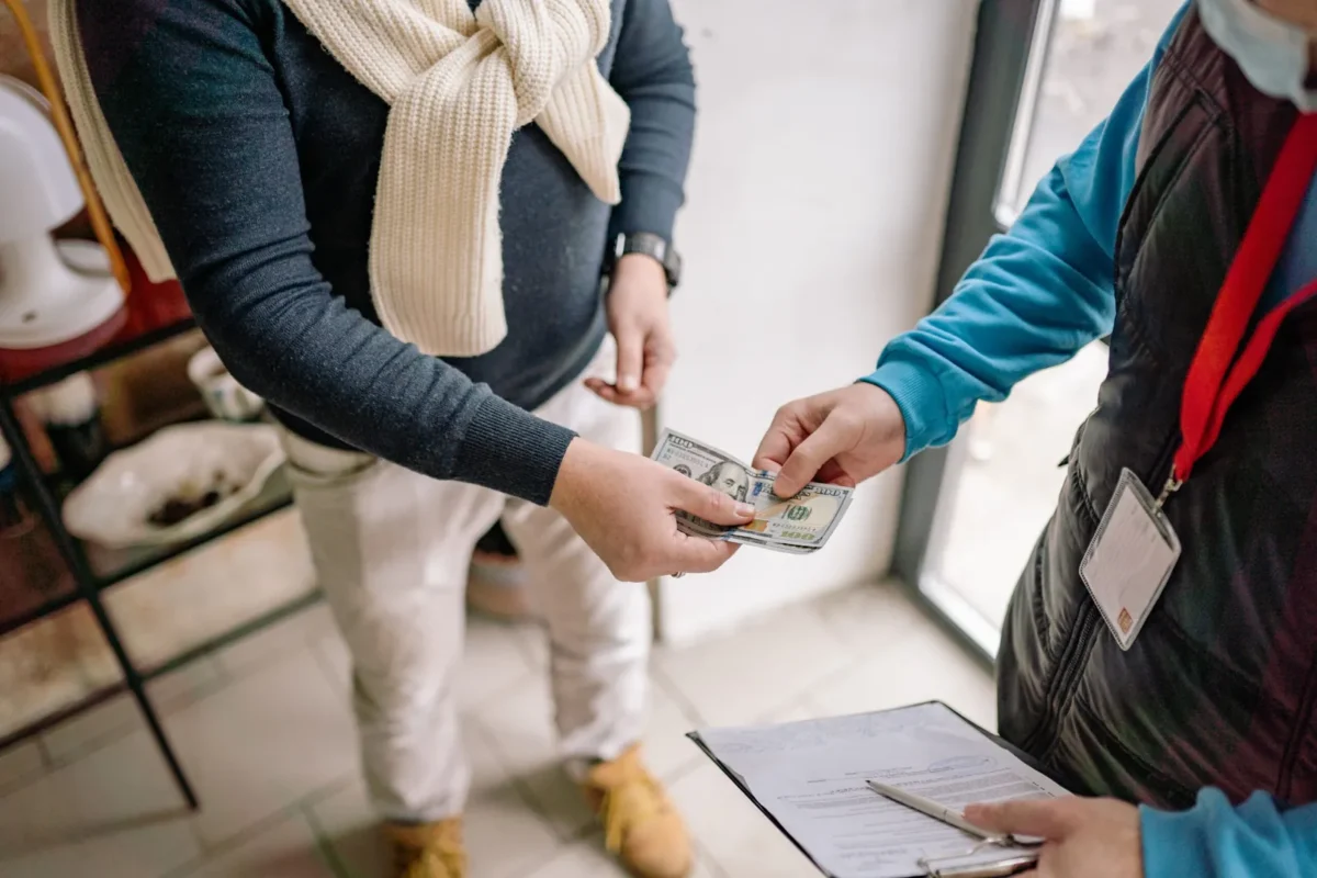 Buyer handing cash to a person holding a clipboard