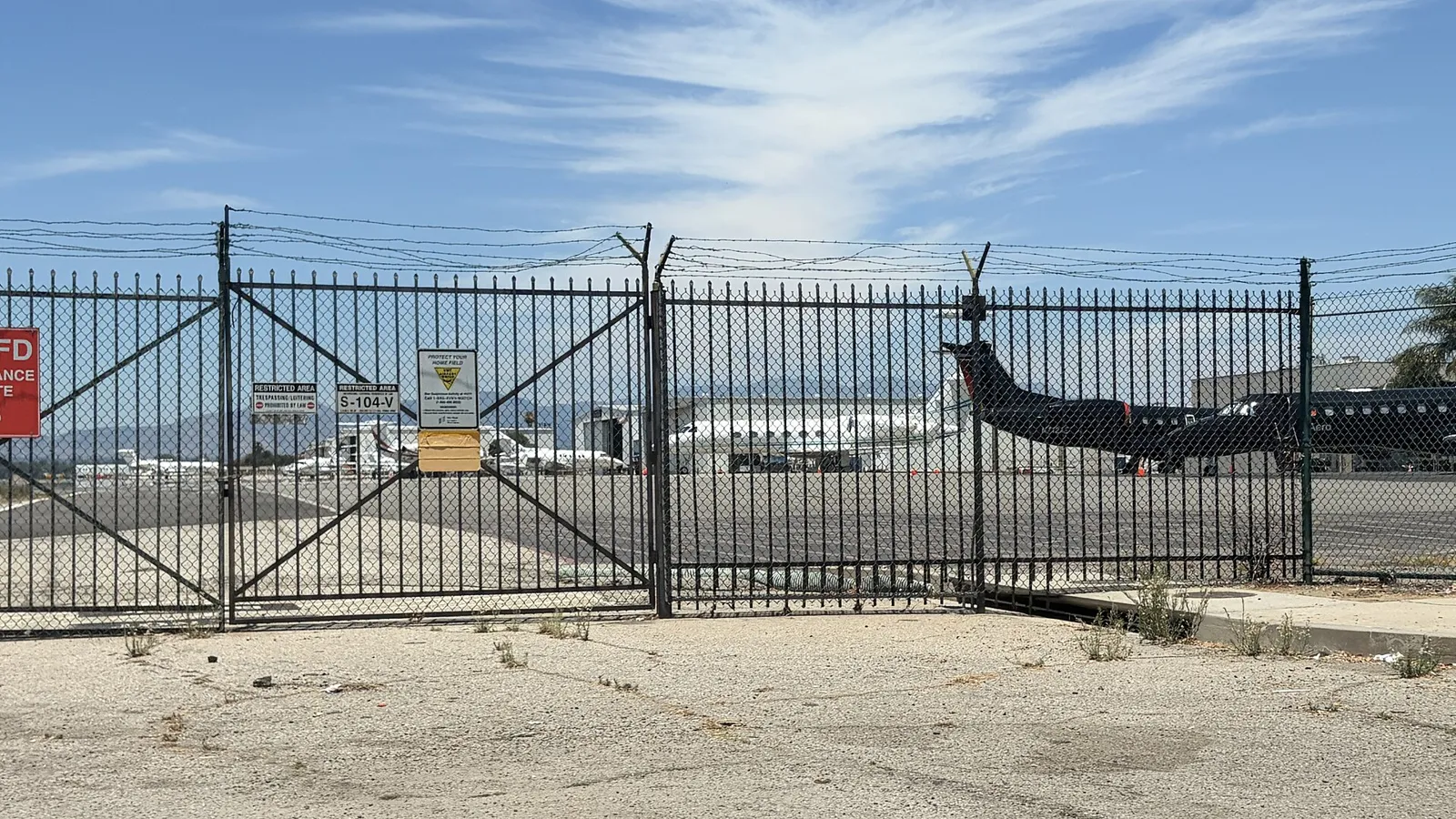Business jets parked behind a security fence at Van Nuys Airport