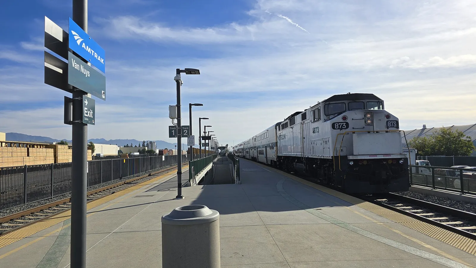 Metrolink train boarding passengers at the Van Nuys station platform